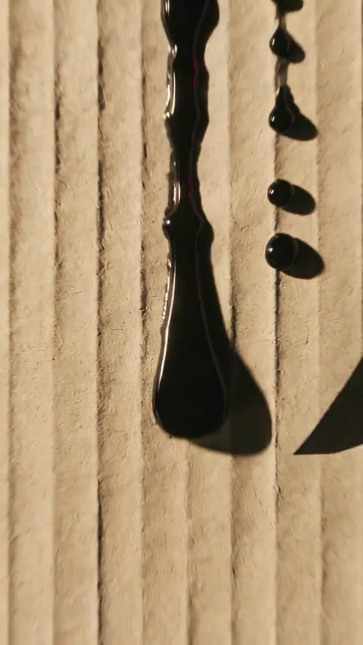 Ink spreads across paper before revealing a designer arranging a poster